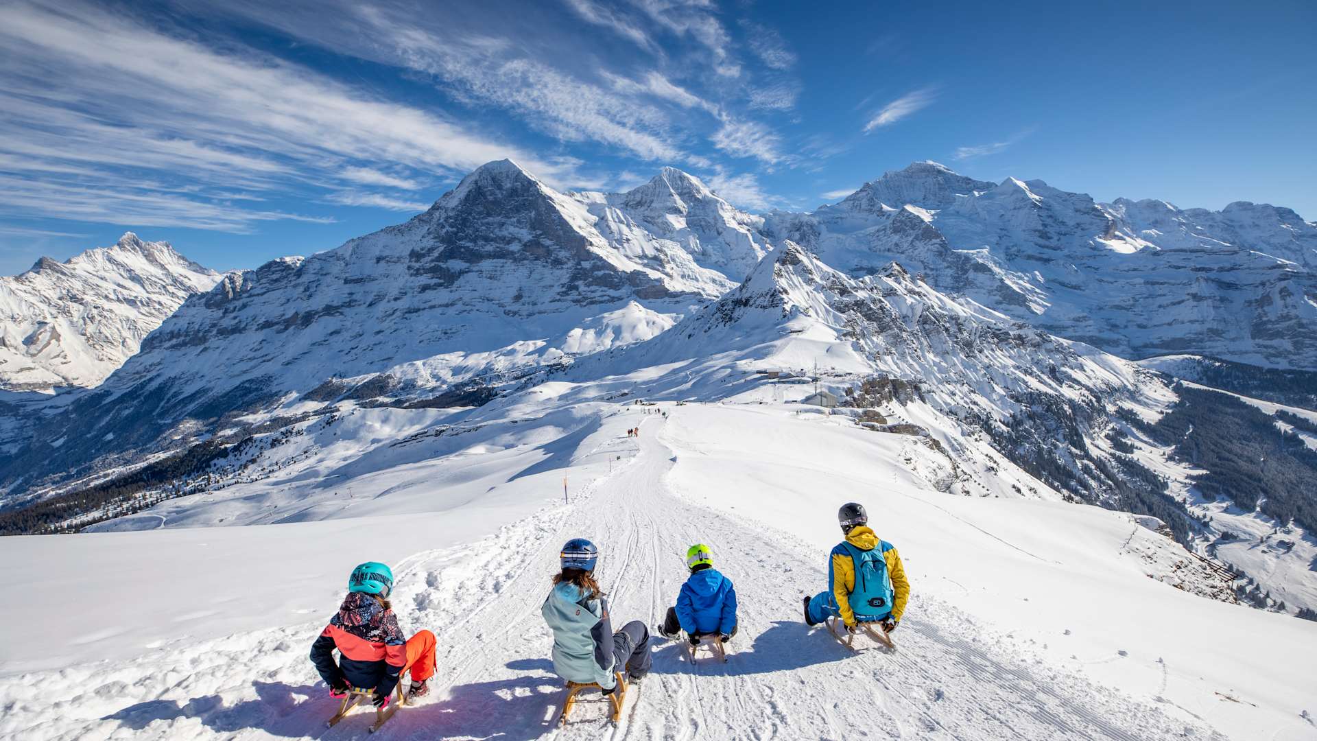 Family sledging at Männlichen in front of Eiger, Mönch and Jungfrau